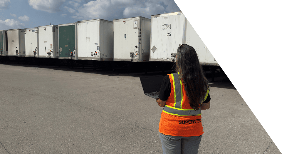 Worker in high-visibility vest managing yard operations with trailers in background